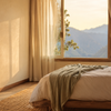 Gemütliches Schlafzimmer in der Abendsonne mit Moskitonetz-Baldachin, Diffuser mit Lavendel auf dem Nachttisch und Bergblick durchs Fenster